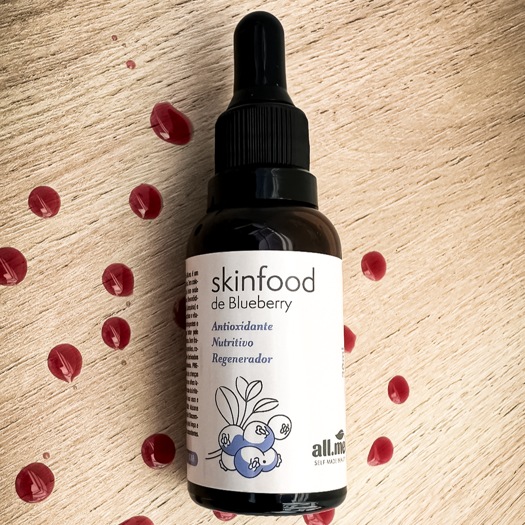 Frasco Ambar com roluto em adesivo escrito Skinfood de Blueberry, Antioxidante, Nutritivo e Regenerador. Ele está sobre uma madeira e tem alguns pingos do produto vermelho que é o extrato puro de mirtilo.