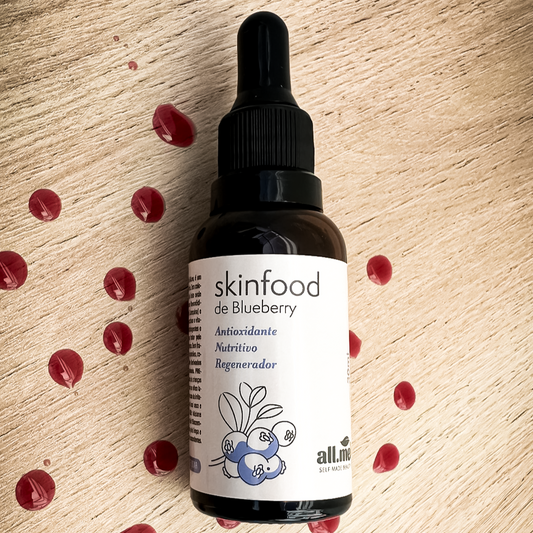 Frasco Ambar com roluto em adesivo escrito Skinfood de Blueberry, Antioxidante, Nutritivo e Regenerador. Ele está sobre uma madeira e tem alguns pingos do produto vermelho que é o extrato puro de mirtilo.